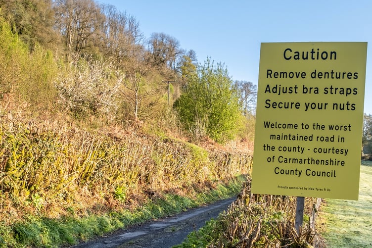 The sign near the Abergorlech Road in Carmarthenshire in Wales. See SWNS story SWLNpothole. Residents fed-up with potholes have installed a fake road sign warning drivers to 'adjust bra straps', 'remove dentures' and 'secure their nuts'. Locals led by John Burton, 68, stuck up the hilarious sign claiming they are being 'ignored' by the council.The sign was put up yesterday (26/4) near the Abergorlech Road in Carmarthenshire in Wales.It says: "Caution. Remove dentures. Adjust bra straps. Secure your nuts.