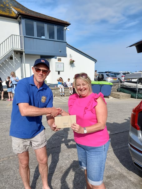 Saundersfoot Duck Race prize winner Deb, with Rotarian Paul Bannister handing over the winnings