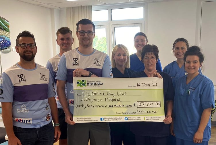 Pictured, left to right: Fundraisers Marc, Guto and Ll r present the cheque for £27,500 to Liliana Guta, Senior Sister; Holly Golden, Trainee Haematology Nurse Specialist; Jenny James, Senior Sister; Georgia Savage, Staff Nurse; Amy Rees-Thomas, Staff Nurse.