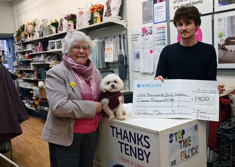 Cancer Research Tenby Shop Manager Ki Howells receives a cheque for £1,400 from Maureen Lower MBE, seen with dog Sammy.