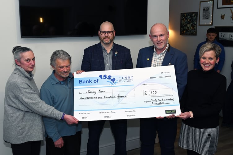Tenby Boxing Day Swim president Chris Osborne, chairman Sam Skyrme-Blackhall and the mayor of Tenby, Dai Morgan, present the Sandy Bear cheque to the charity's business development manager, Martin Jones.