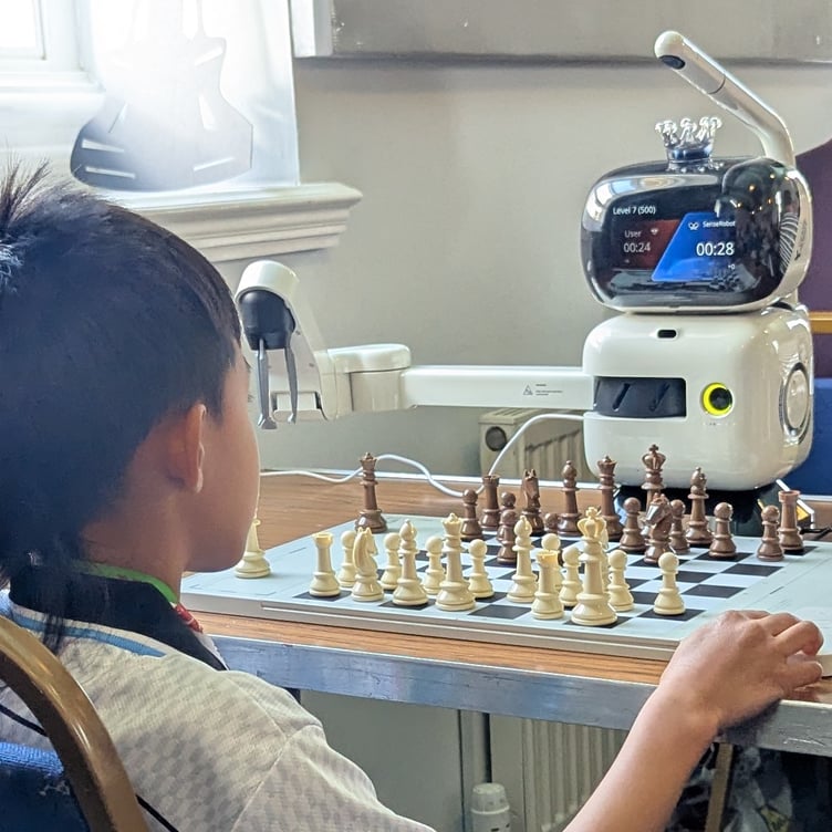 Boy playing chess robot