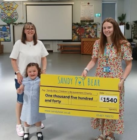 Gemma’s wife Sarah and their daughter presenting their generous donation to Leah at Sandy Bear Children’s Bereavement Charity